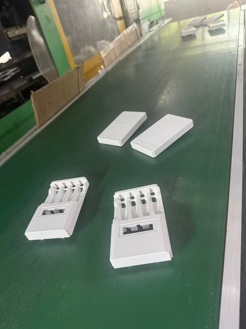 White PC+ABS enclosure components moving along a production conveyor